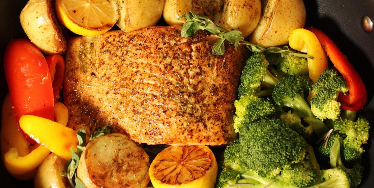 Greek-seasoned salmon fillet roasted in one pan with baby potatoes, peppers, broccoli and lemon
