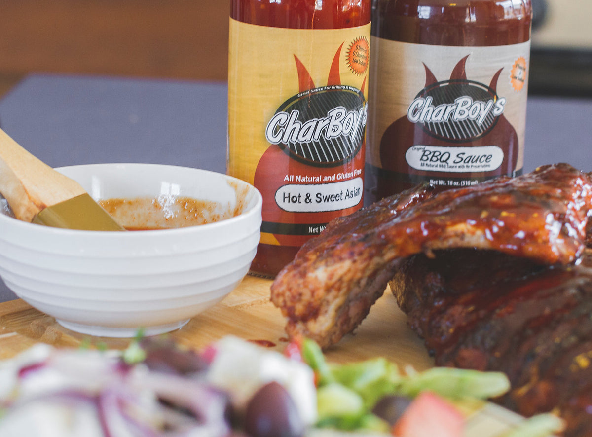 CharBoy's Hot & Sweet Asian and BBQ sauce bottles beside barbecued ribs