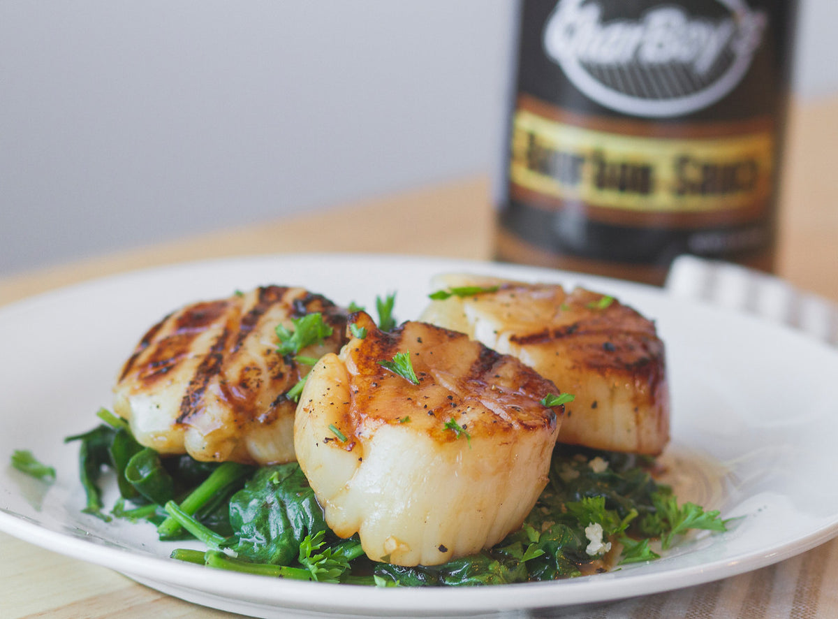Seared scallops on greens with a bottle of CharBoy's sauce