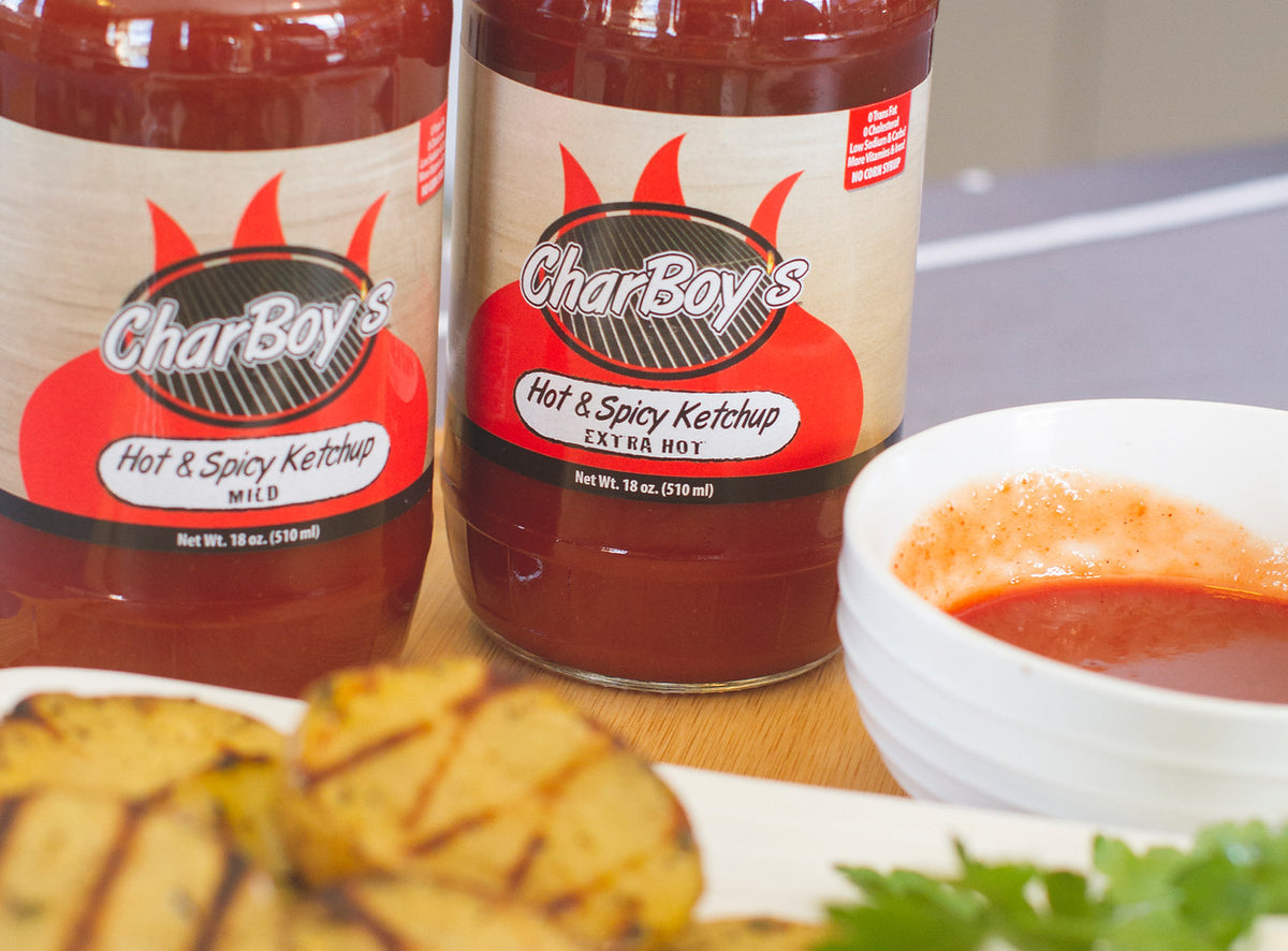 Two bottles of CharBoy's Hot & Spicy Ketchup with grilled potatoes and a dipping bowl