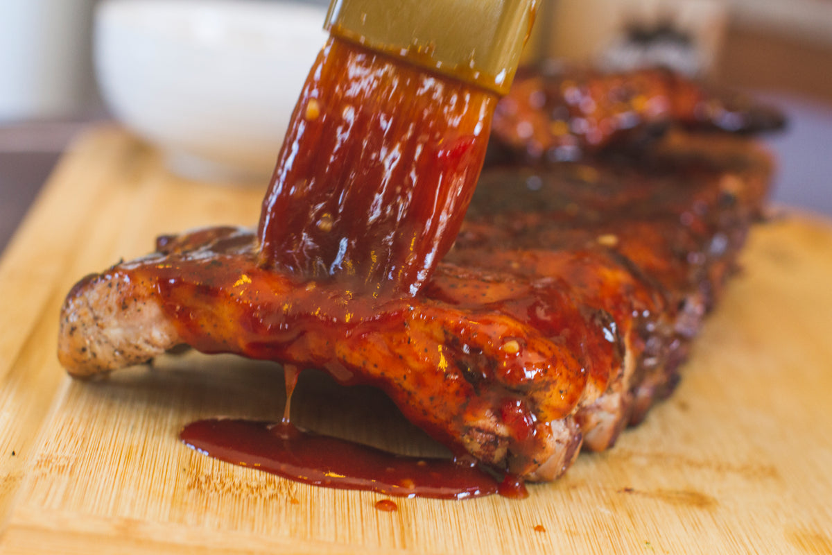 CharBoy's Southern BBQ Sauce brushed over baby back ribs on a wooden board